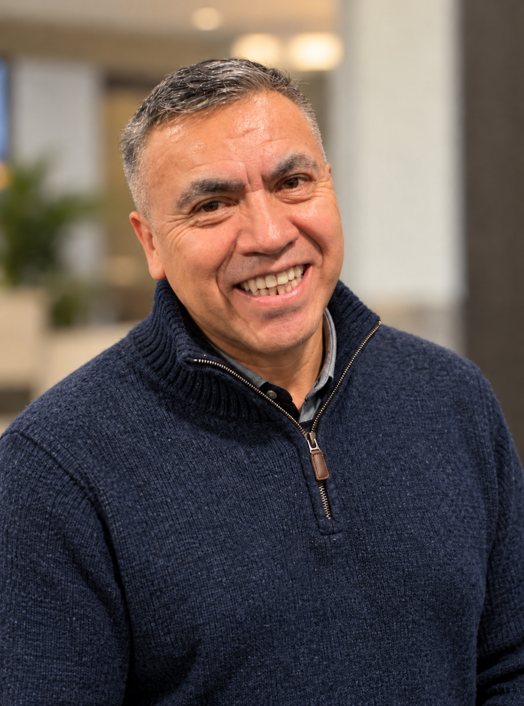 Carmelo Carvente sonriendo con suéter azul marino